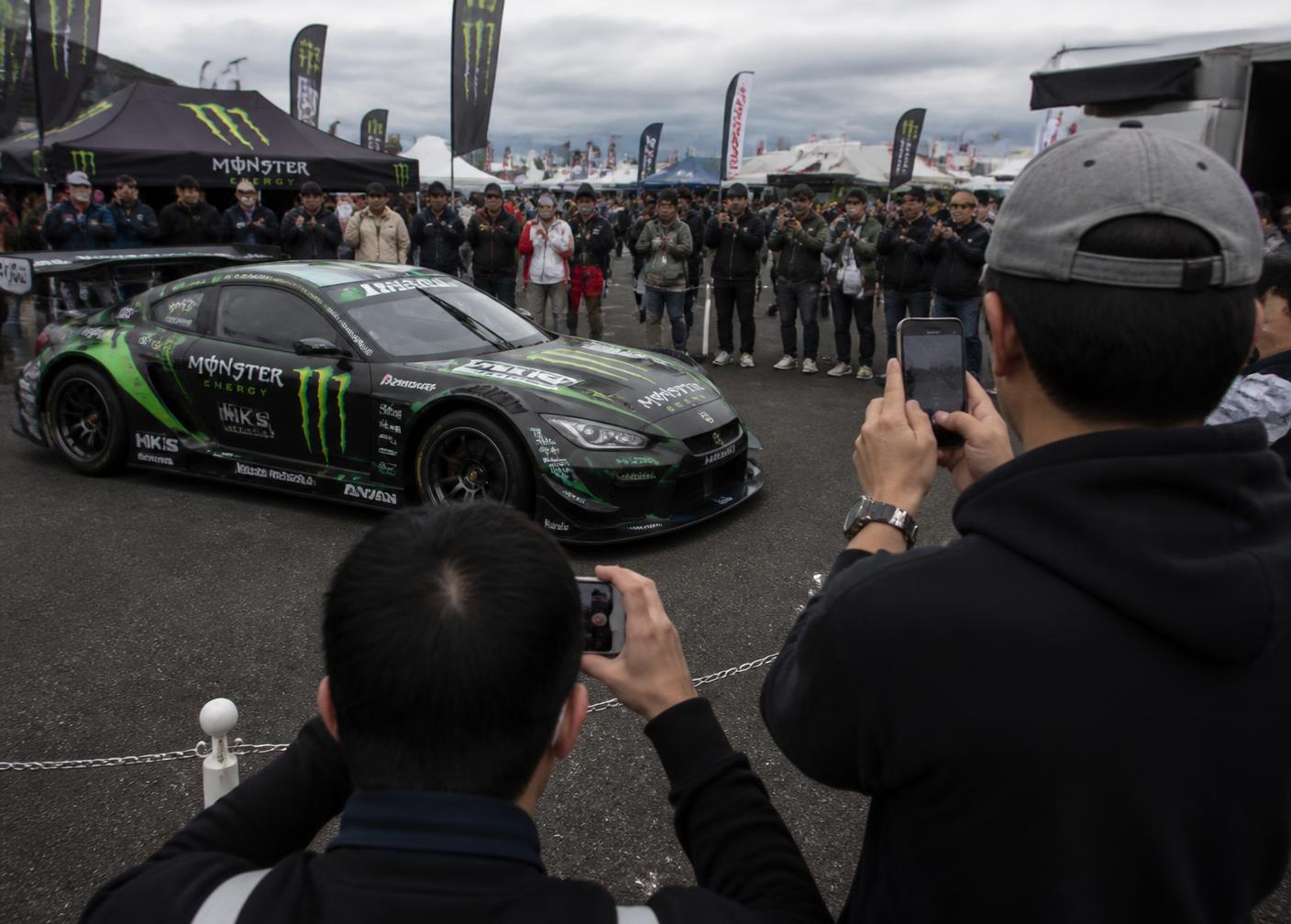 Spectators photographing a sponsored race car at a car show